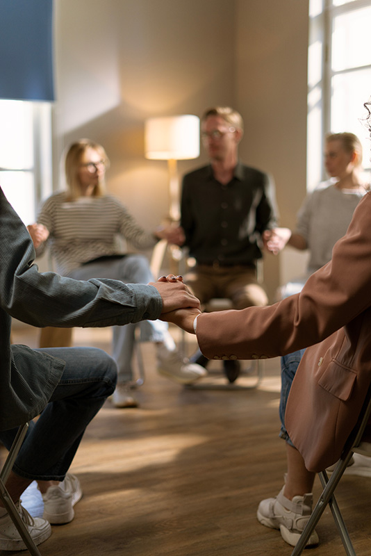 People in group therapy hold hands as a group to show support in an opioid rehab program.