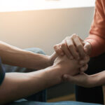 A person reaches out to another person for support in addiction recovery.