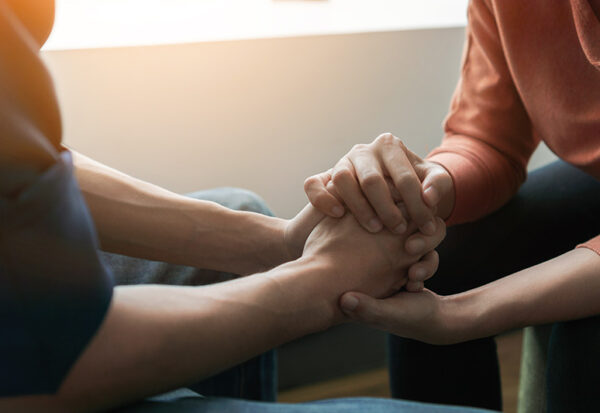 A person reaches out to another person for support in addiction recovery.