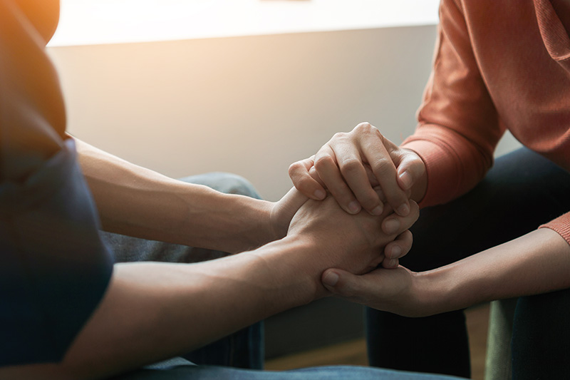 A person reaches out to another person for support in addiction recovery.