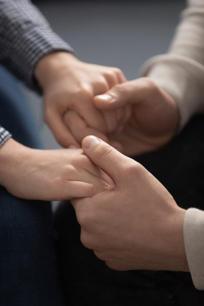 A person holds another person's hands in a gesture of support.