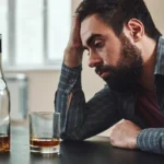 A man drinks an alcoholic beverage.