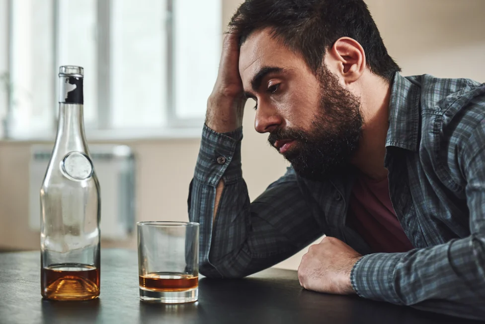 A man drinks an alcoholic beverage.